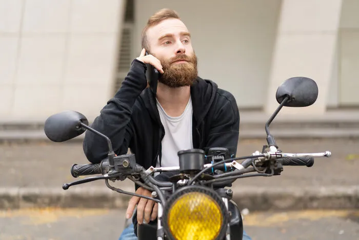 Man on motorcycle using phone with focused expression