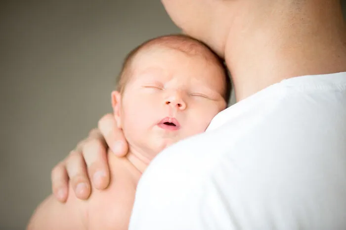 Close-up of a newborn baby sleeping on an adult's shoulder