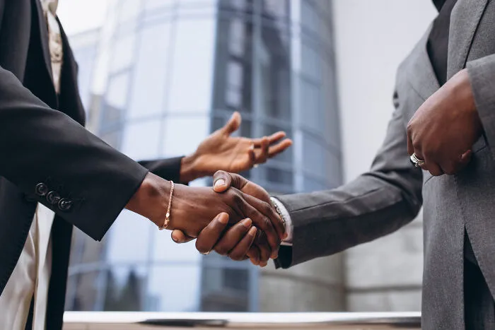 Two businesspeople shaking hands in front of office building