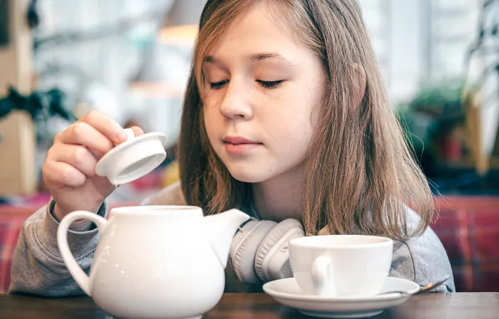 A teenage girl looking inside a teapot, showcasing independence apart from helicopter parenting control