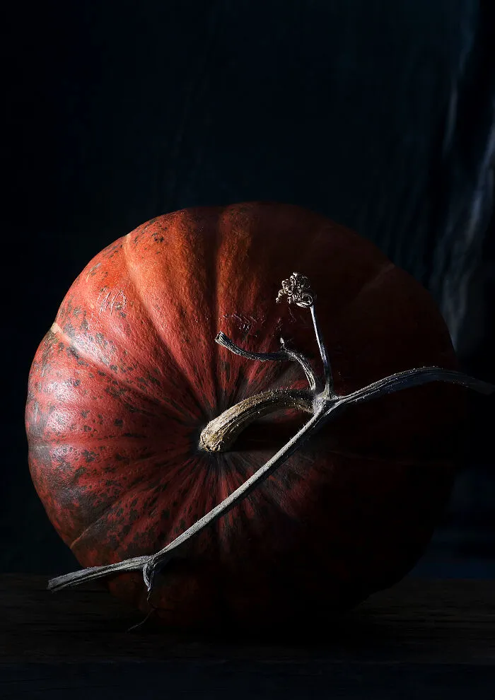Close-up of a large orange-red pumpkin against a dark background