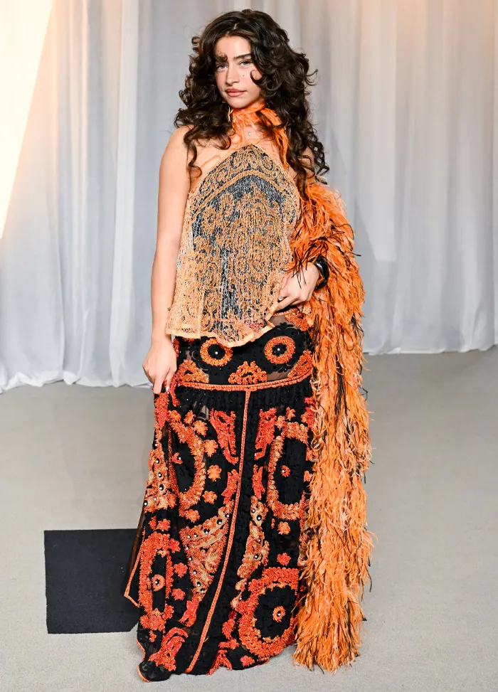Black and orange embroidered gown with feathered shawl at Academy Gala