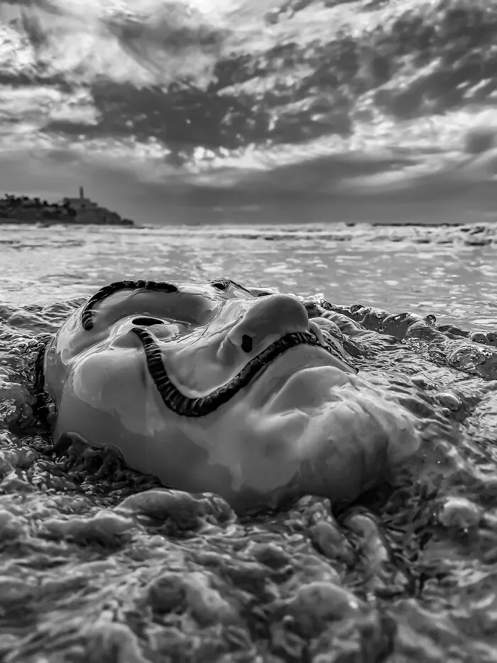 Black and white iPhone photo of Salvador Dali mask in ocean waves