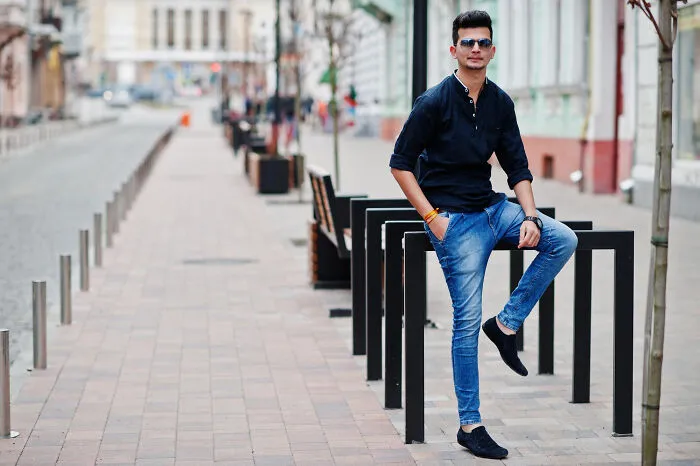 Stylish man posing in dark shirt and jeans on a city street before a second date
