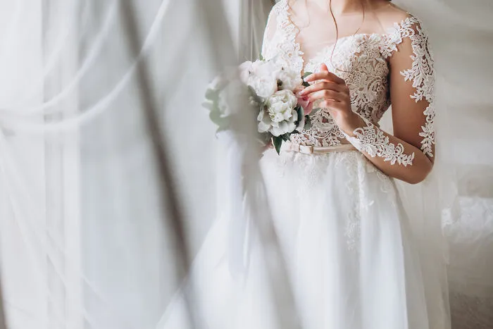 A bride wearing an elegant white lace wedding dress holding a flower bouquet, symbolizing love in divorce stories.