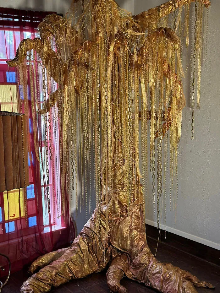 Artistic home makeover featuring a tall, decorative golden tree sculpture adorned with metallic chains.