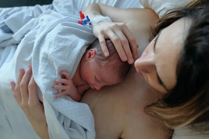 Newborn baby resting on mother's chest in hospital setting