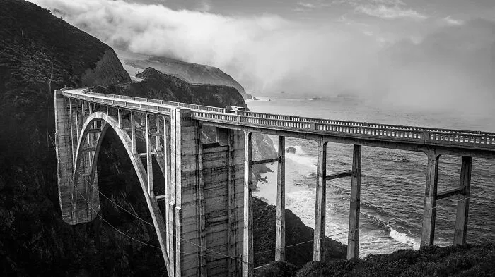 Dramatic black-and-white photo of a coastal bridge surrounded by fog from Exposure One Awards.