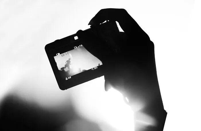 Silhouette of a hand holding a digital camera in a black-and-white photo
