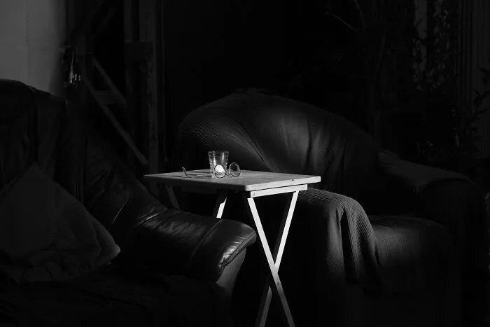 Black-and-white photo featuring dark armchairs and a small side table