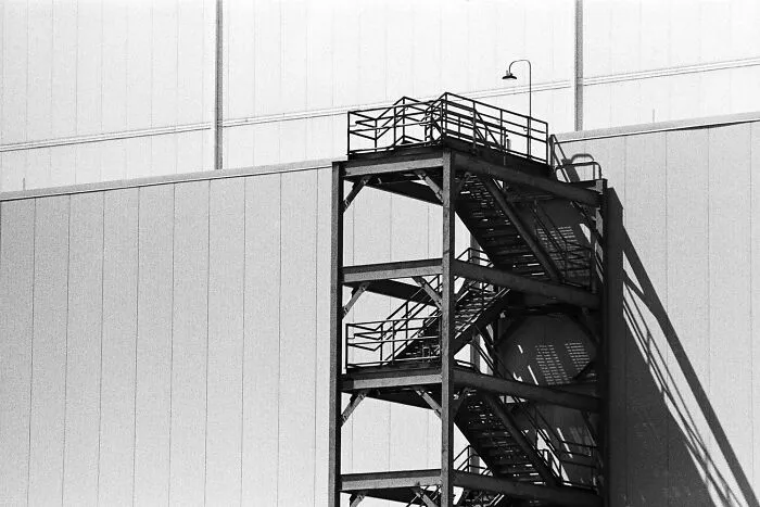 Architectural black-and-white photos of an industrial metal fire escape staircase against a building wall.