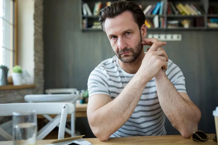 An upset man sitting at a desk, representing emotional conflict in personal divorce stories.
