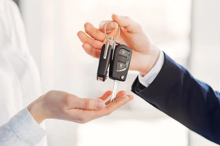 One person handing car keys to another, depicting asset division in real-life divorce stories.