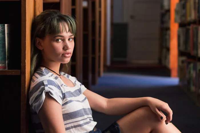 A young woman sitting on a library floor, thinking about her lifelong friendships that fizzled out.