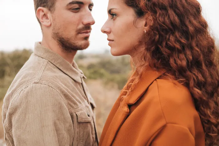 A man and woman staring intensely at each other outdoors, reflecting awkward moments on a date.
