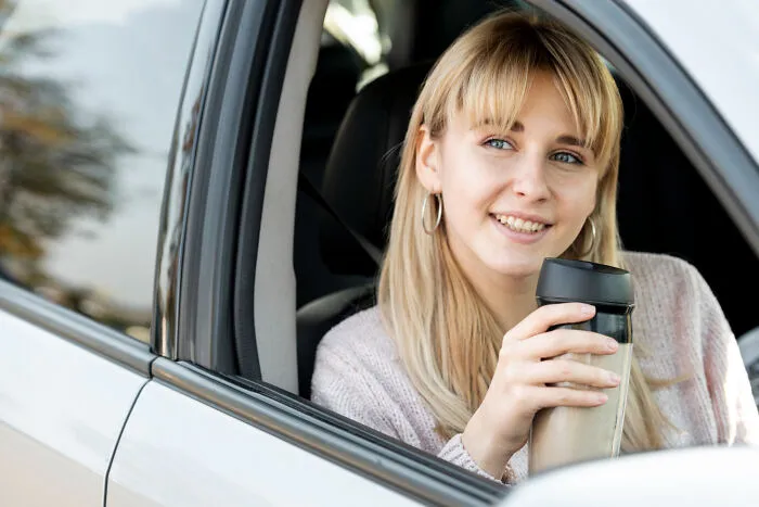 A blonde woman in a car holding a travel mug, illustrating everyday encounters where strangers said alarming things