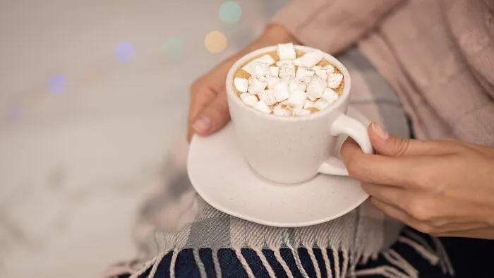 Person holding hot chocolate while discussing stories of helicopter parenting