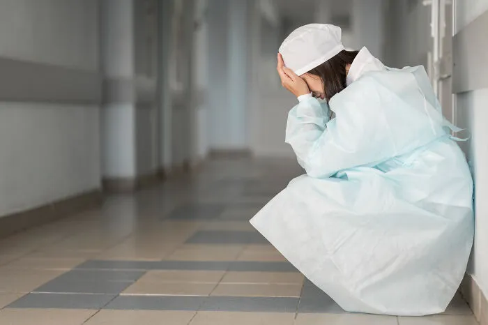Tired healthcare workers sitting on the floor of a hospital hallway in distress