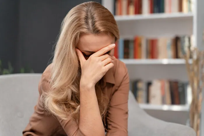 A frustrated woman facepalming at home, considering reasons to skip a second date.