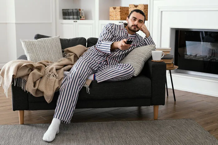Bored man lounging on couch with remote control, choosing to skip a second date