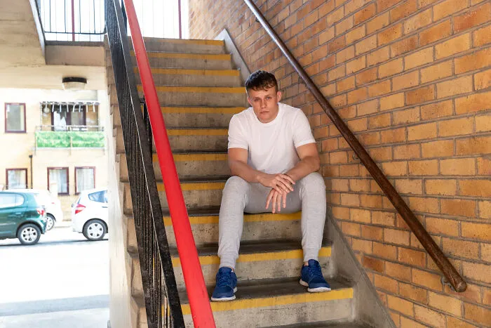 Young man sitting on outdoor stairs looking worried facing scary life challenges