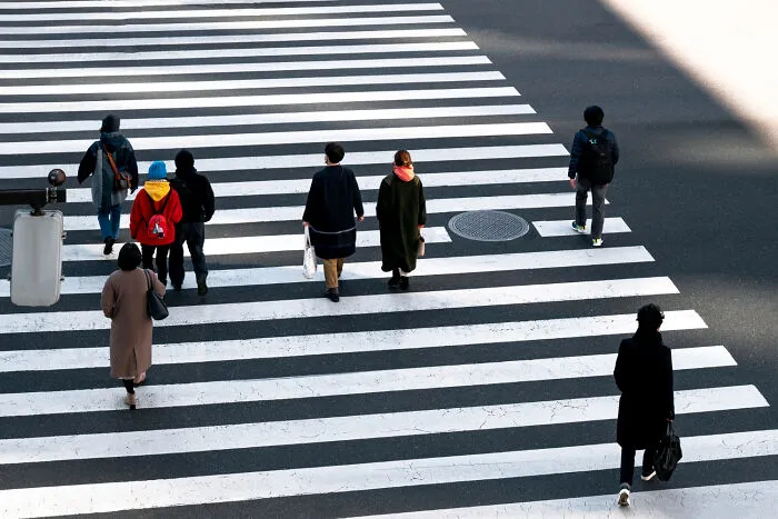 Pedestrians using a zebra crosswalk, following safety guidelines and emergency tips.