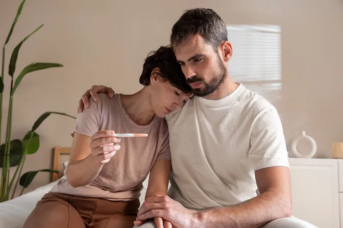 Sad couple holding a pregnancy test, highlighting emotional strain linked to divorce stories.