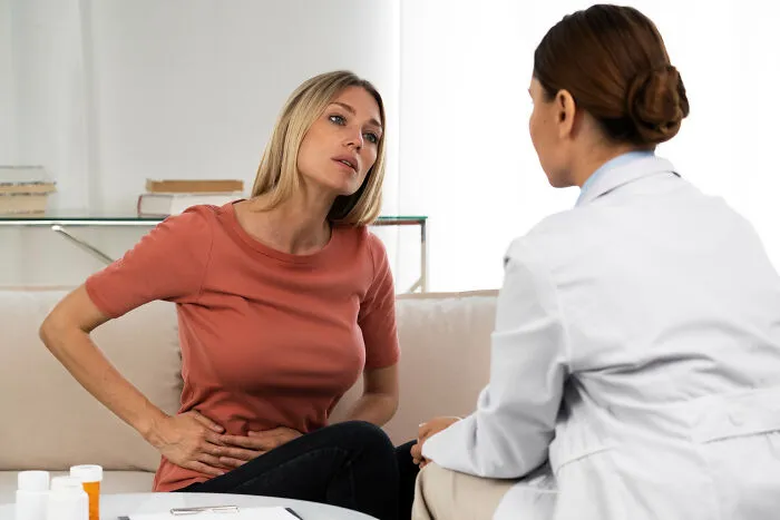 A woman consulting a healthcare worker about abdominal pain