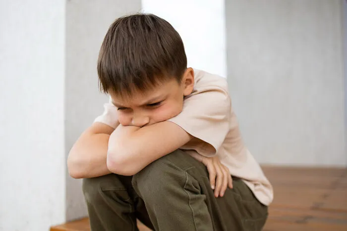 A young boy looking upset and sitting alone during divorce stories.