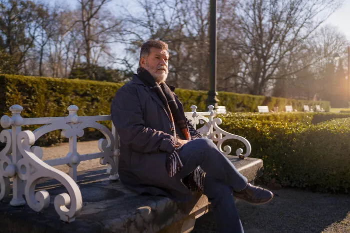 Elderly man sitting on a park bench reflecting on memorable funerals