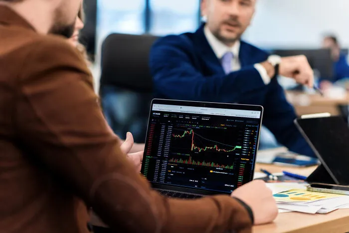 Business meeting with stock trading chart on laptop screen