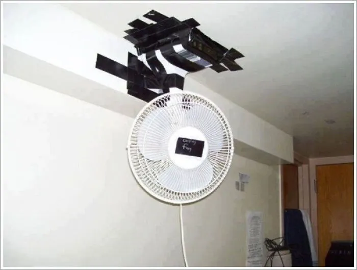 A white desk fan taped to the ceiling with black duct tape, depicting a hilarious renovation fiasco.