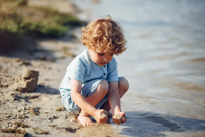 Young boy playing safely at the water edge, representing child safety and emergency tips.