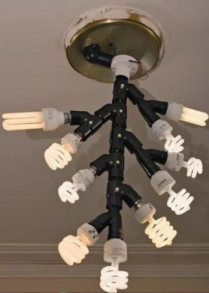 Bizarre branch-shaped light fixture made of pipes and multiple light bulbs, a home improvement fiasco.