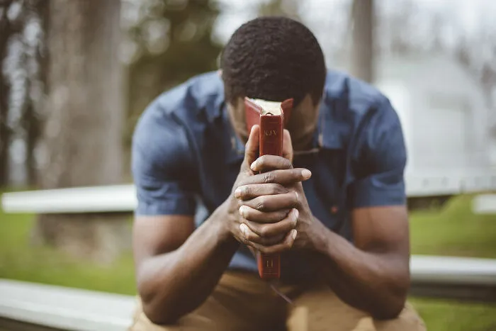 A man praying solemnly, reflecting emotional distress in real-life divorce stories.