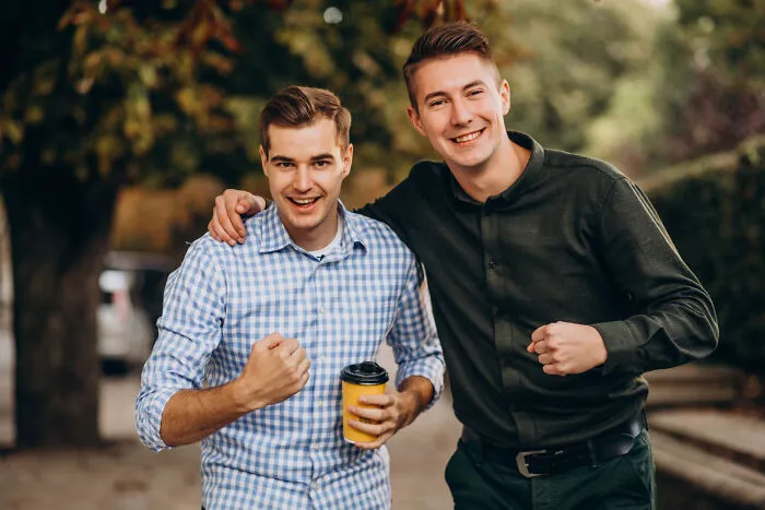 Two happy male friends posing outdoors, representing stories of lifelong friendships.