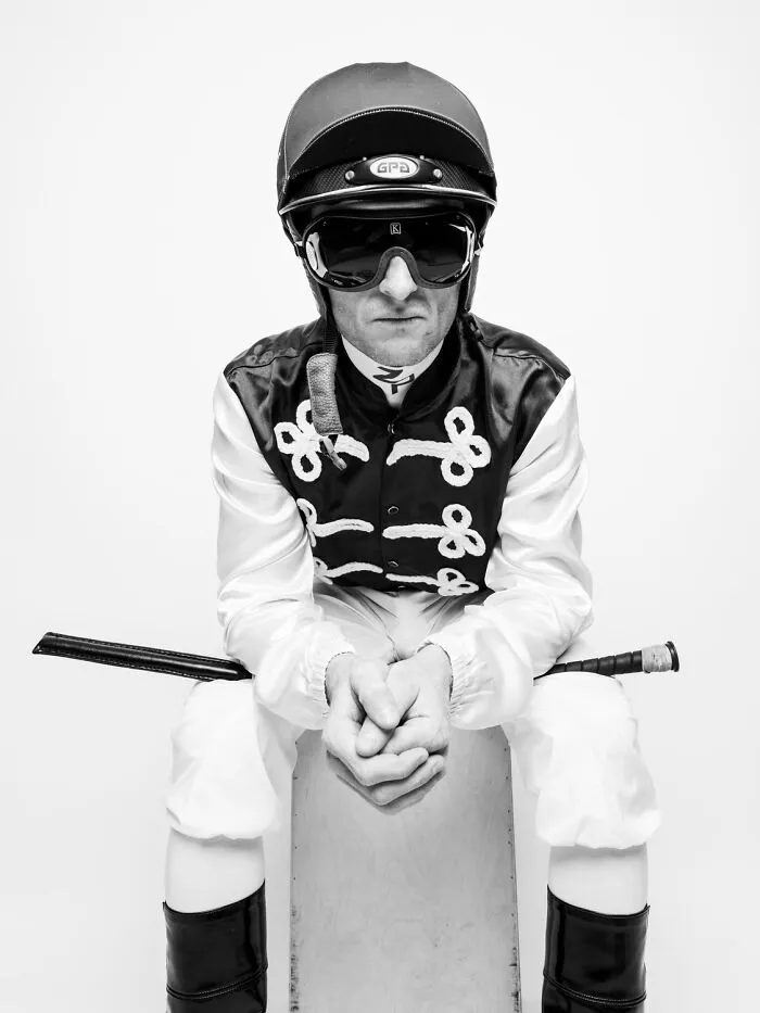 Portrait of a jockey sitting in full gear, part of black-and-white photos for Exposure One Awards