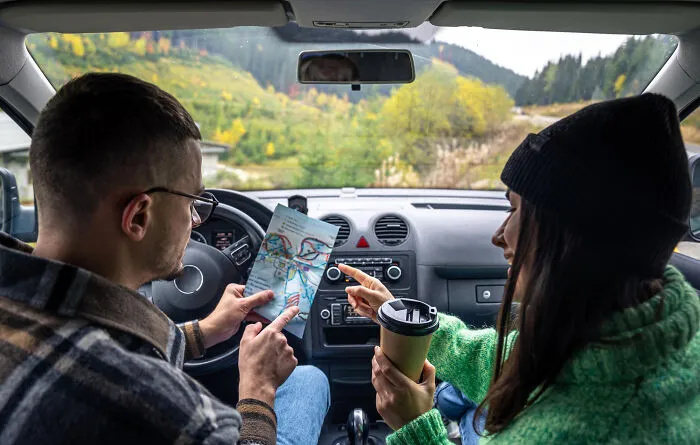 Couple in a car looking at a map, showing partner's navigation mistakes that question their intelligence