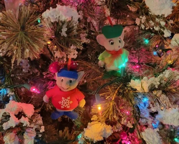 Two vintage mouse ornaments hanging on a decorated Christmas tree, a charming thrift find.