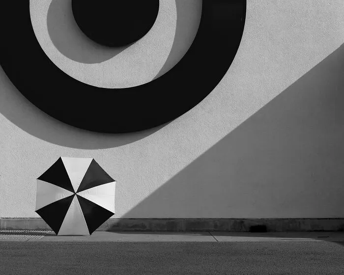 Patterned umbrella sitting below a circular design in black-and-white photos