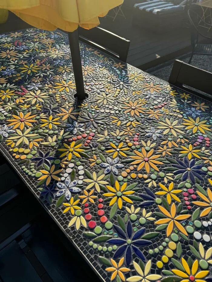 Outdoor table featuring intricate mosaic floral artwork, an example of creativity to save money on decor.