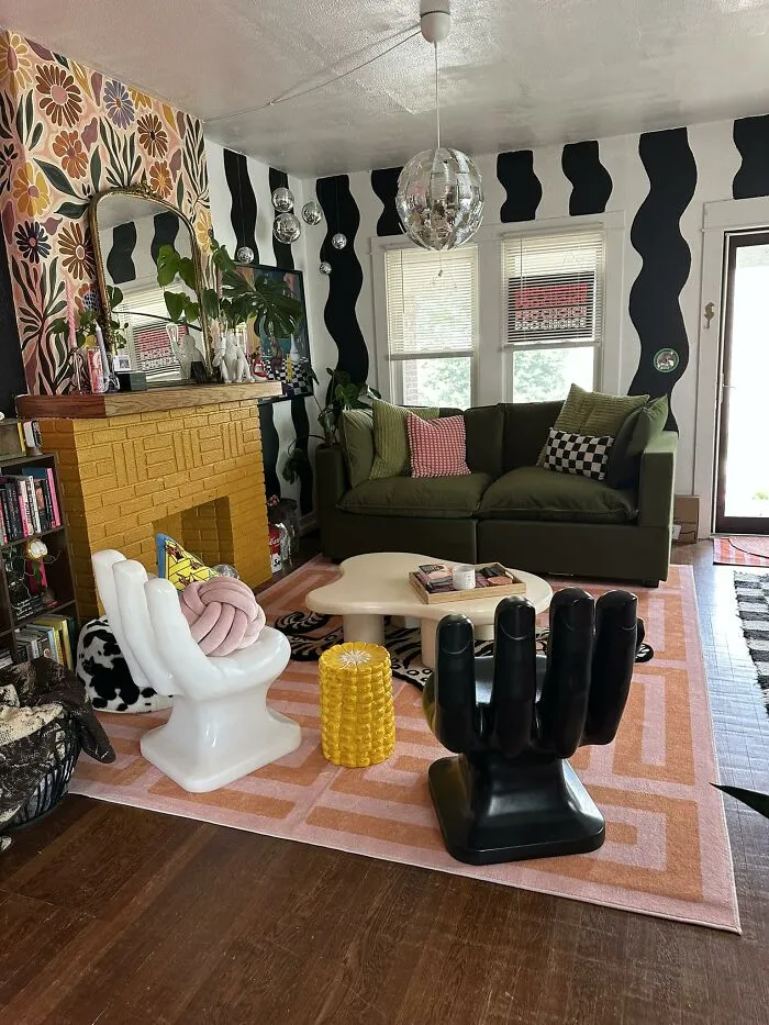 Eclectic living room home makeover with hand-shaped chairs, a yellow brick fireplace, and colorful wallpaper.