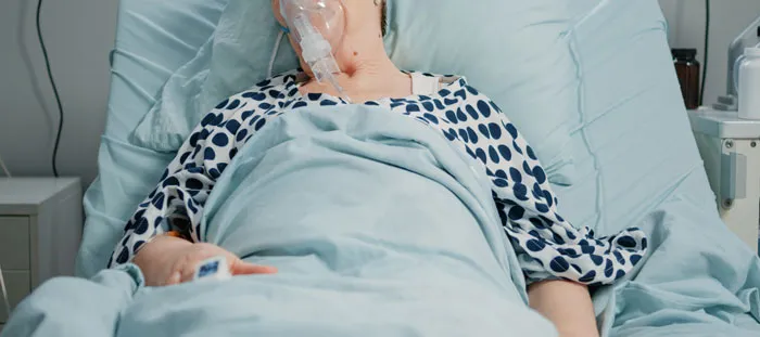 Patient in hospital bed with an oxygen mask, highlighting sad health events in divorce stories.
