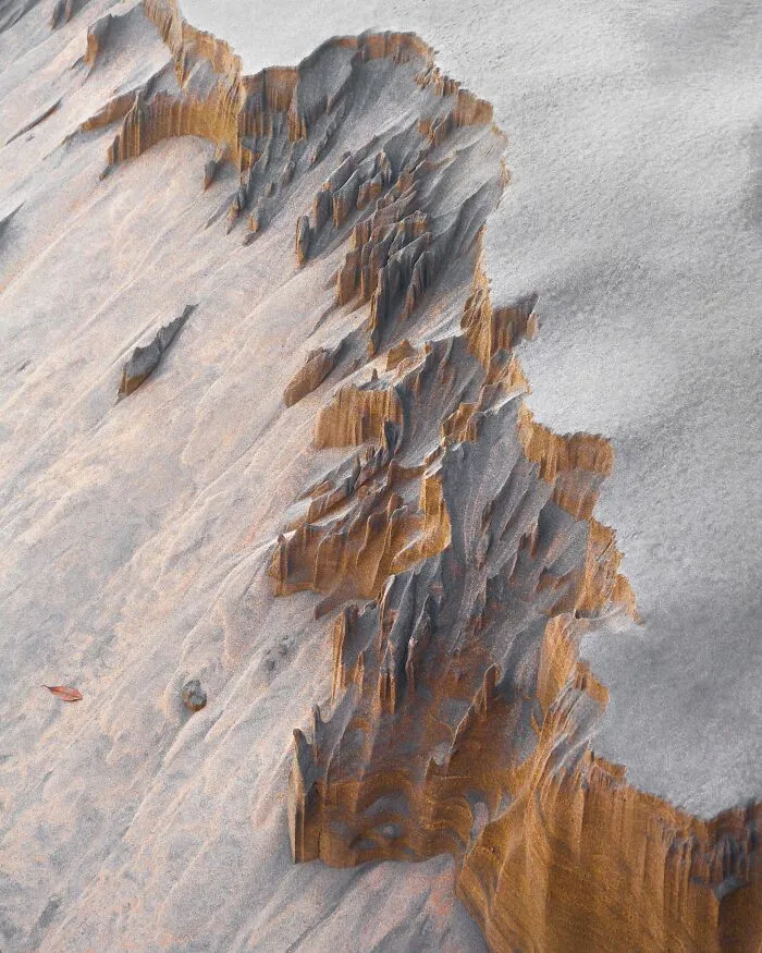 Eroded sand formations along a beach line shown in natural landscape photography.