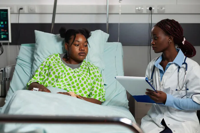 A healthcare worker talking with a patient in a hospital bed