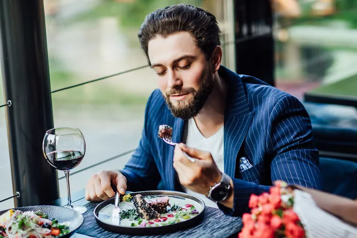 A handsome man enjoying a fancy dinner with wine, showing why people decide to skip a second date.