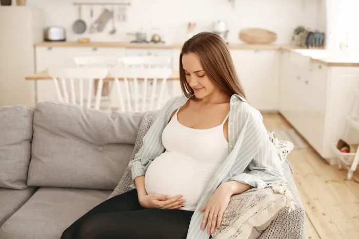 A pregnant woman resting on a sofa, representing complex real-life divorce stories.