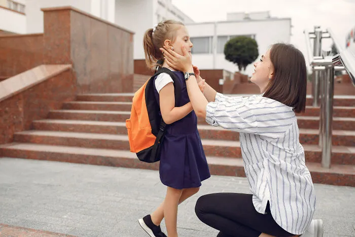 Mother holding her daughter's face before school, illustrating helicopter parenting separation anxiety.