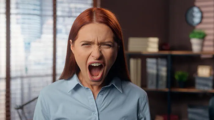 An angry, screaming woman in an office, showcasing conflicts where lifelong friendships fizzled out.