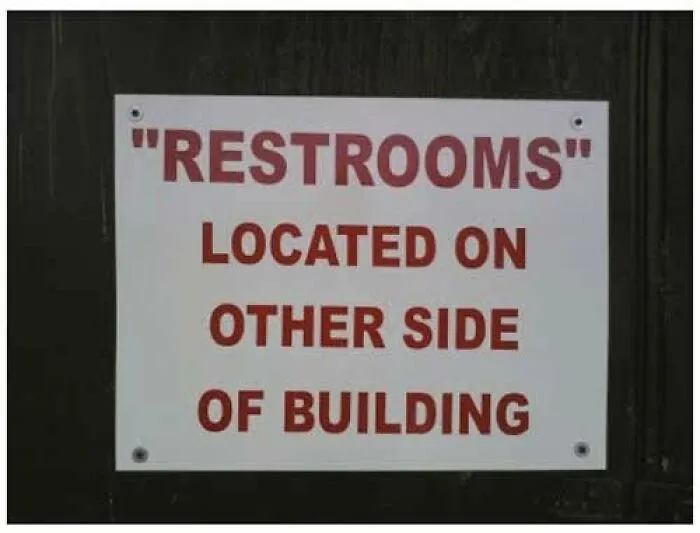Directional sign showing misused quotation marks around the word Restrooms